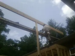 Carpenter setting a ridge beam over a new addition frame — Ice Dam Removal by Roofing Brothers in Latta