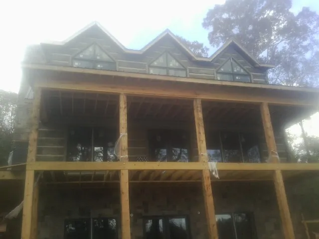 Dormers and porch framing on a large log home under construction — Roof Coating work by our crew in Latta