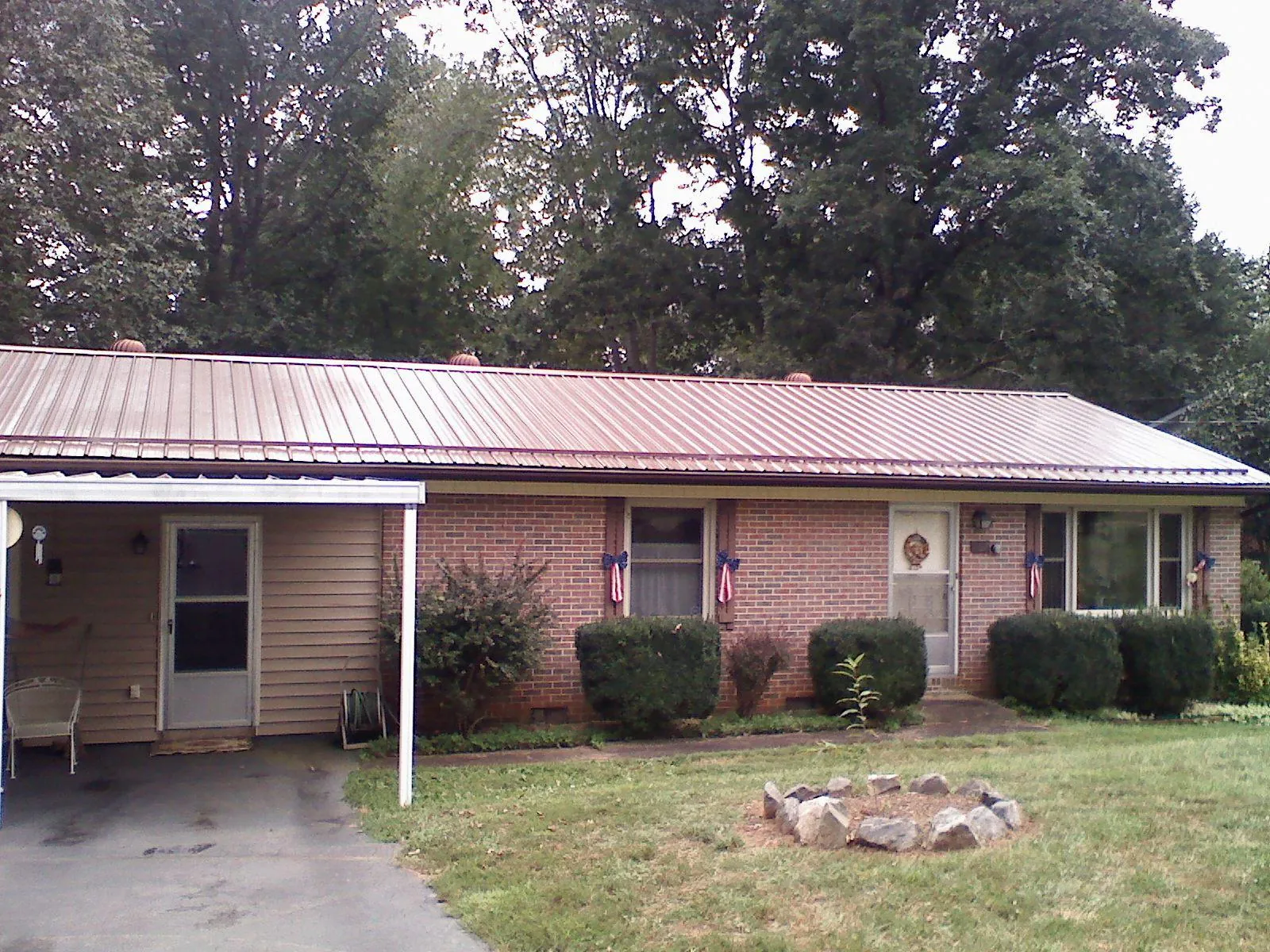 Bronze metal roof and carport on a brick ranch home — Roof Repair work by our crew in Latta