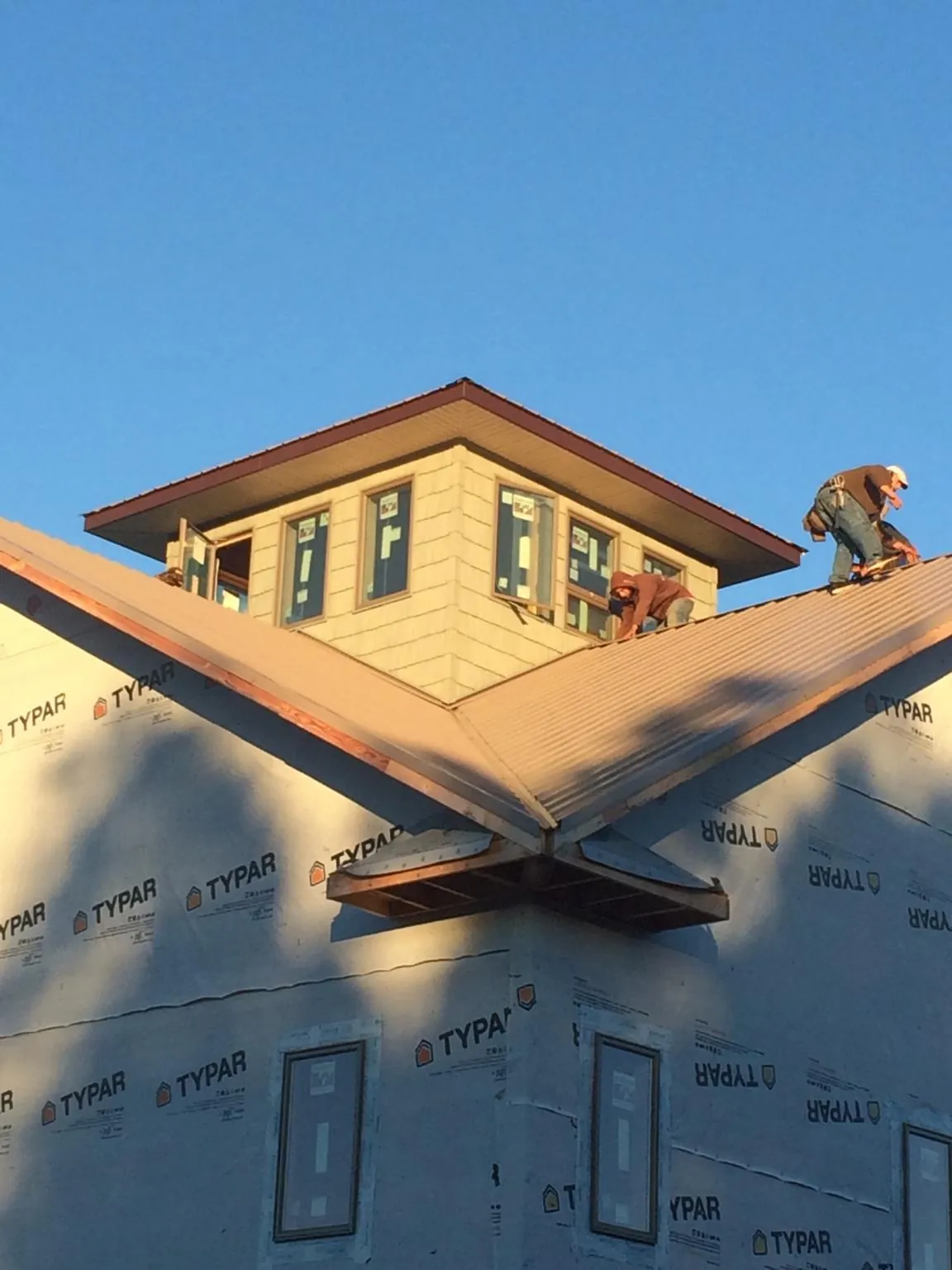 Roofers working around a rooftop cupola on a new metal roof at sunset — Roof Waterproofing in Latta by Roofing Brothers